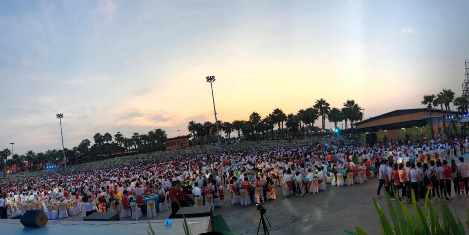 Large-scale outdoor banquet at dusk for several thousand guests, organized by AIT